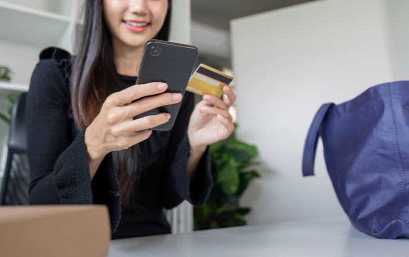 Smiling woman shopping online with a credit card and smartphone, highlighting seamless eCommerce sales and digital trade.